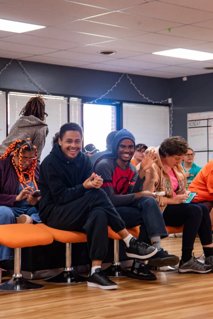 Adults smiling and sitting together during a group activity at an adult day support program.