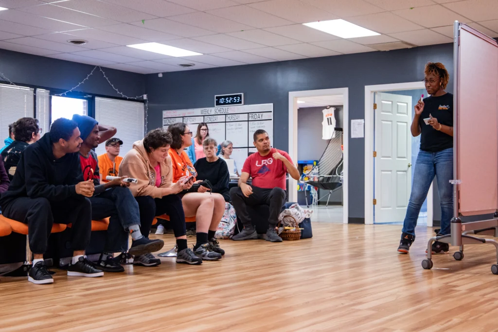 Staff member leading a group activity with adults seated together at an adult day support program.