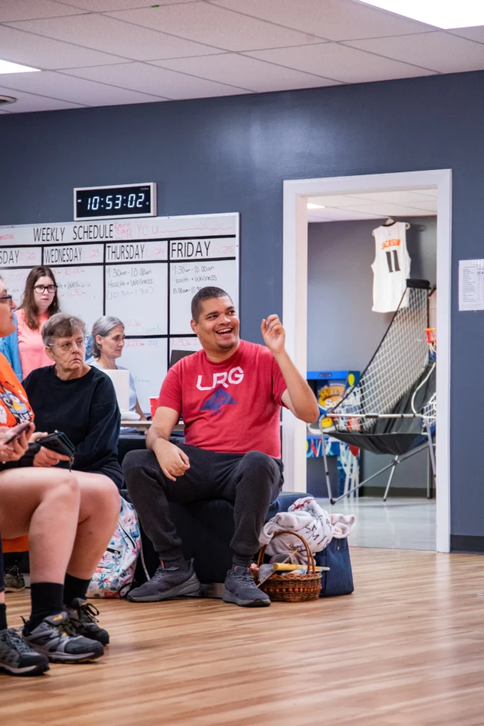 Adults laughing and talking together during a group activity at an adult day support program.