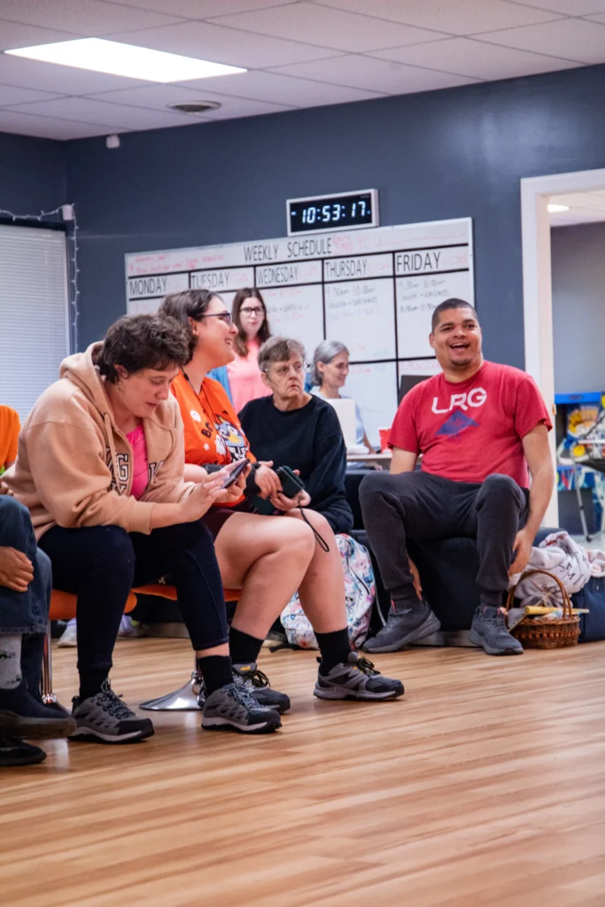 Adults laughing and talking together during a group activity at an adult day support program.