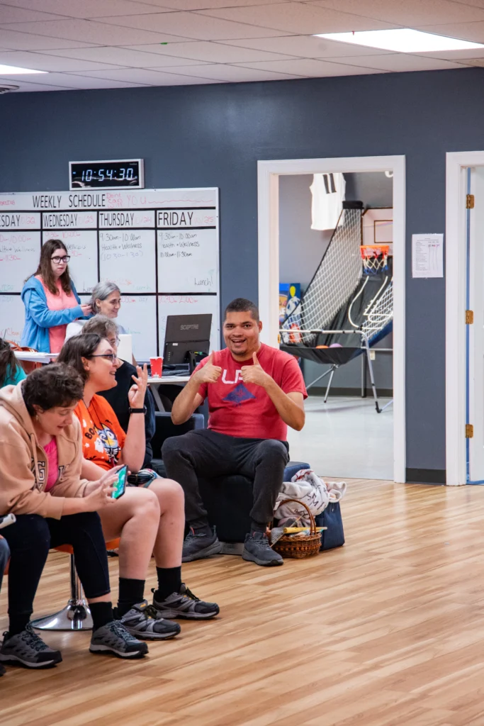 Adults and staff sitting together during a group activity at an adult day support program.