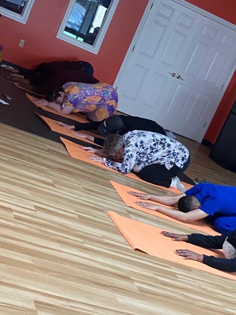 Adults stretching on yoga mats during a group wellness activity at an adult day support program.