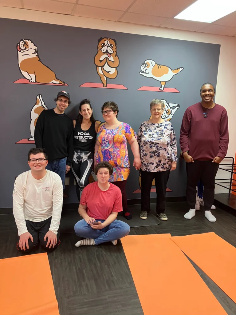 Adults and instructor posing together after a yoga activity at an adult day support program.