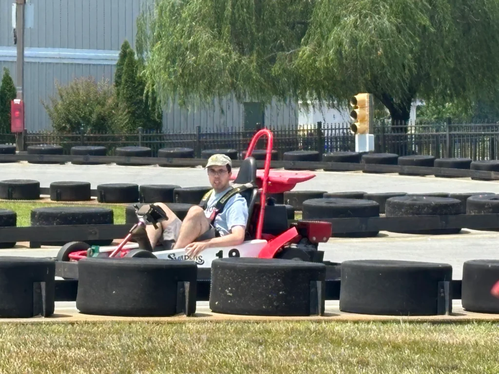 Adult member driving a go-kart on an outdoor track during a community outing.