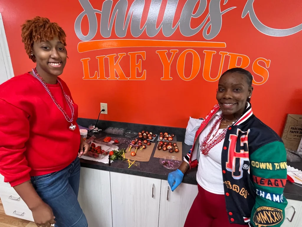 Adult member and staff member smiling during a craft activity at Smiles Like Yours.