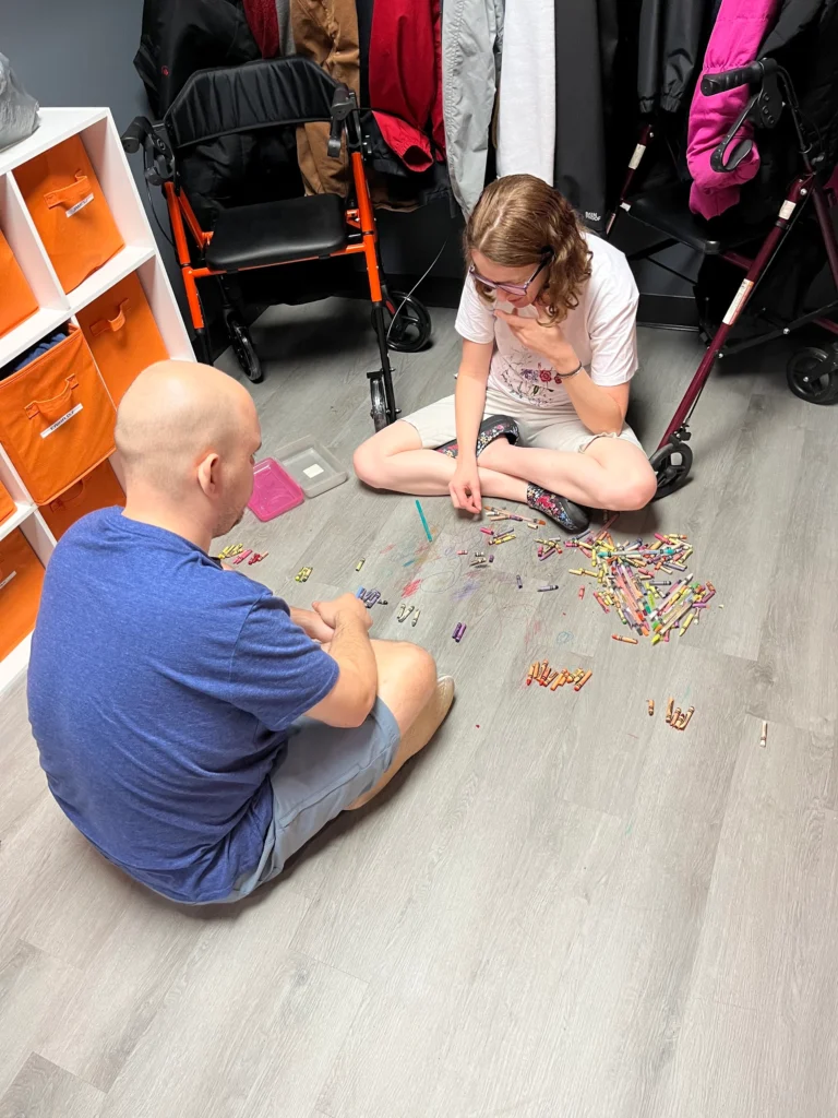 Adults sitting on the floor and playing a hands-on game during an adult day support program activity.