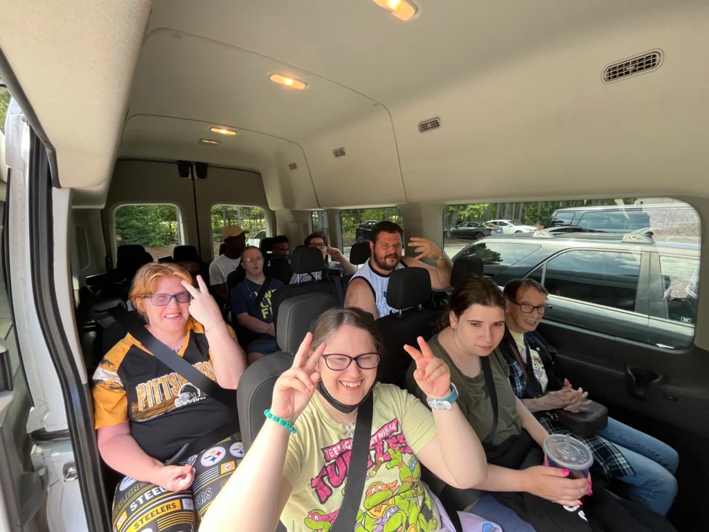 Adults with developmental disabilities traveling together in a van for a supported community outing.