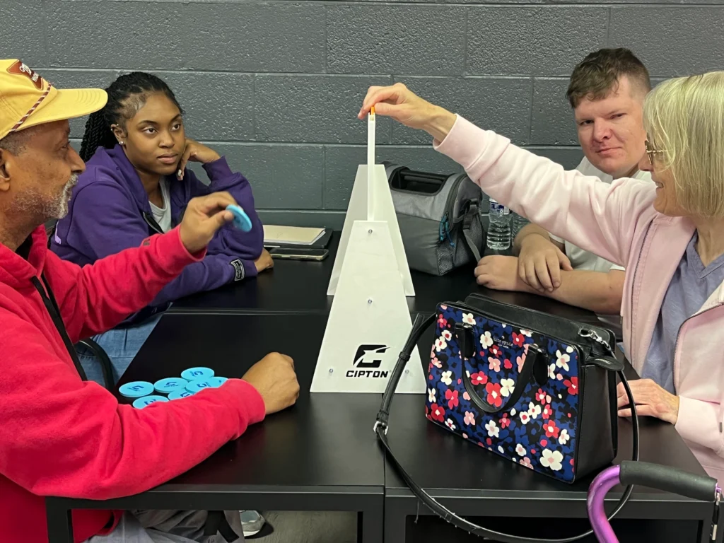 Adults taking turns during a table game activity at an adult day support program.
