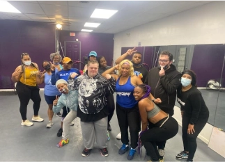 Group of diverse individuals posing together in a fitness studio, showcasing community engagement and support for individuals with disabilities, aligned with Smile Like Yours services.