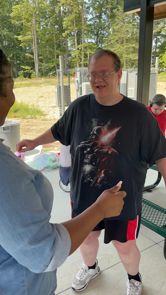 Adult member talking with staff during an outdoor community activity at an adult day support program.