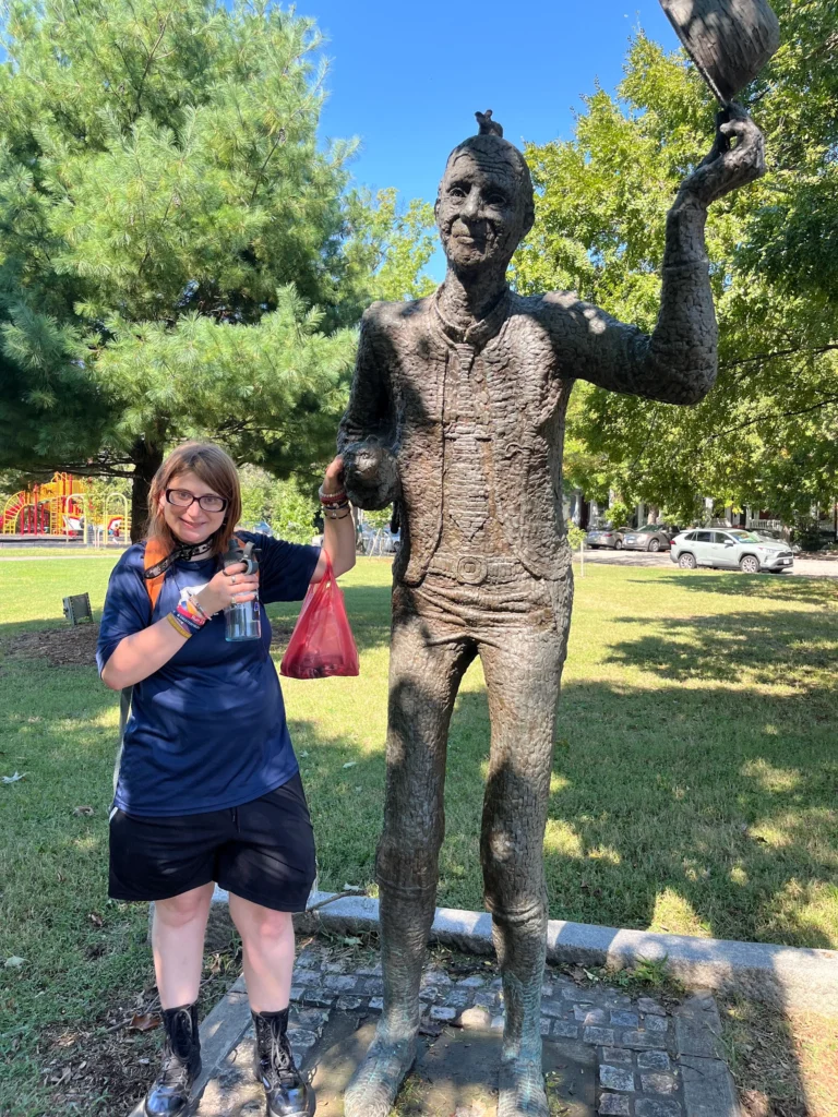 Adult member standing beside a statue during a park community outing.