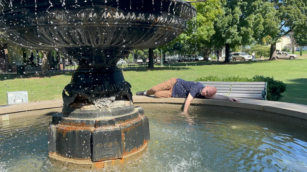 Adult member resting near a park fountain during a community outing with an adult day support program.