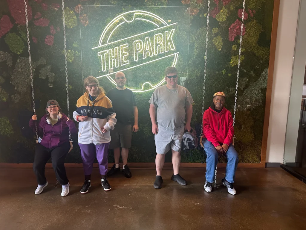 Adults from an adult day support program posing together at The Park during a community outing.