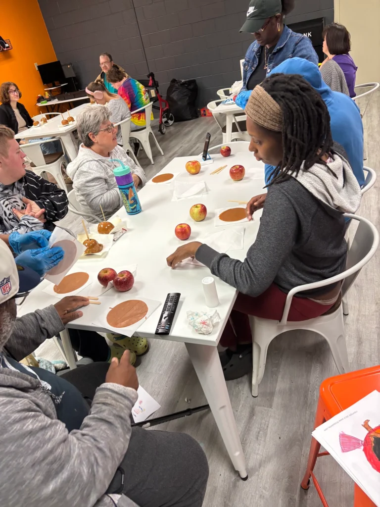 Adults and staff working on an apple craft activity together at an adult day support program.