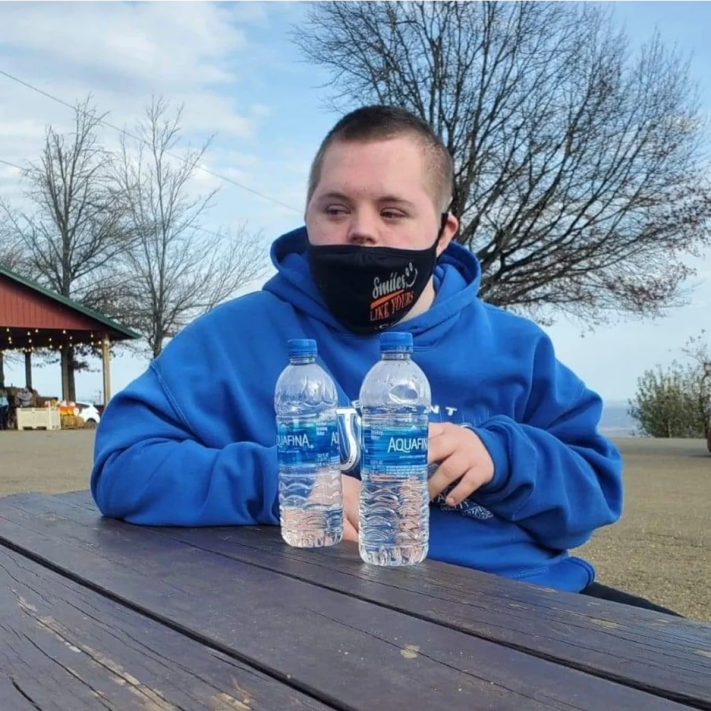 Adult member sitting at an outdoor table during a community outing with an adult day support program.
