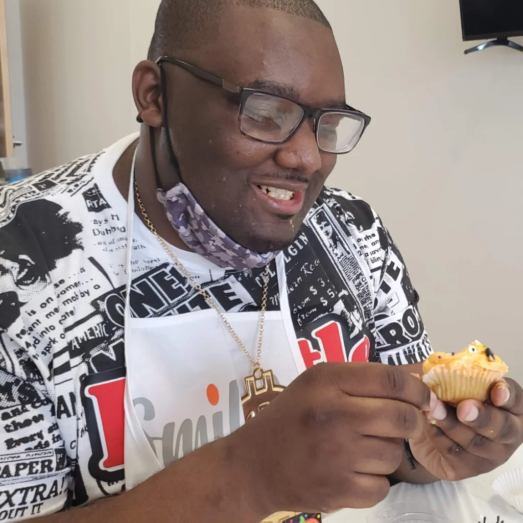 Adult member decorating a cupcake during a hands-on cooking activity at an adult day support program.