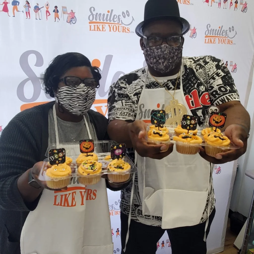 Adults showing decorated Halloween cupcakes during a cooking activity at an adult day support program.