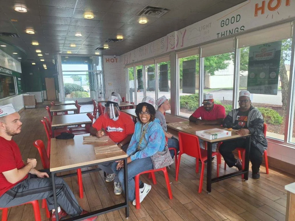Adults seated together at Krispy Kreme during a community outing with an adult day support program.