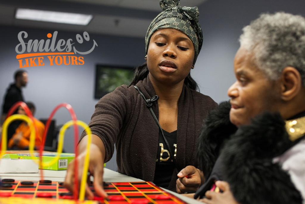  Adults with developmental disabilities taking turns during a hands-on table game at Smiles Like Yours.