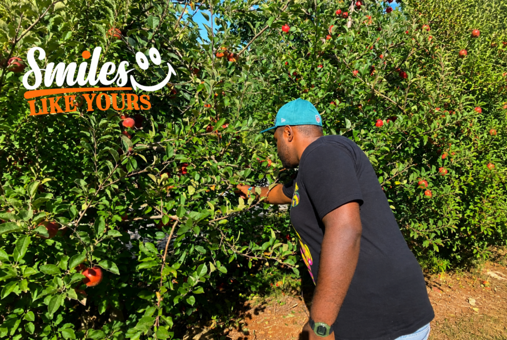  Adult with a developmental disability picking an apple during a sensory-friendly community outing.