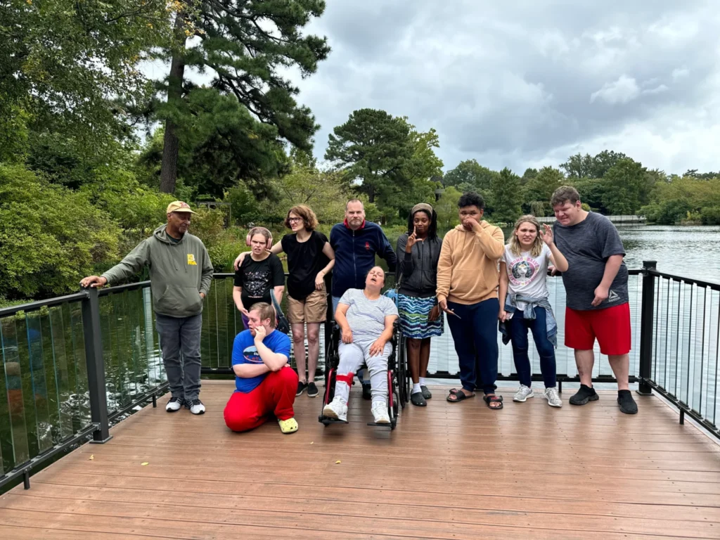 Adults with developmental disabilities enjoying a supported community outing by a lake with Smiles Like Yours.