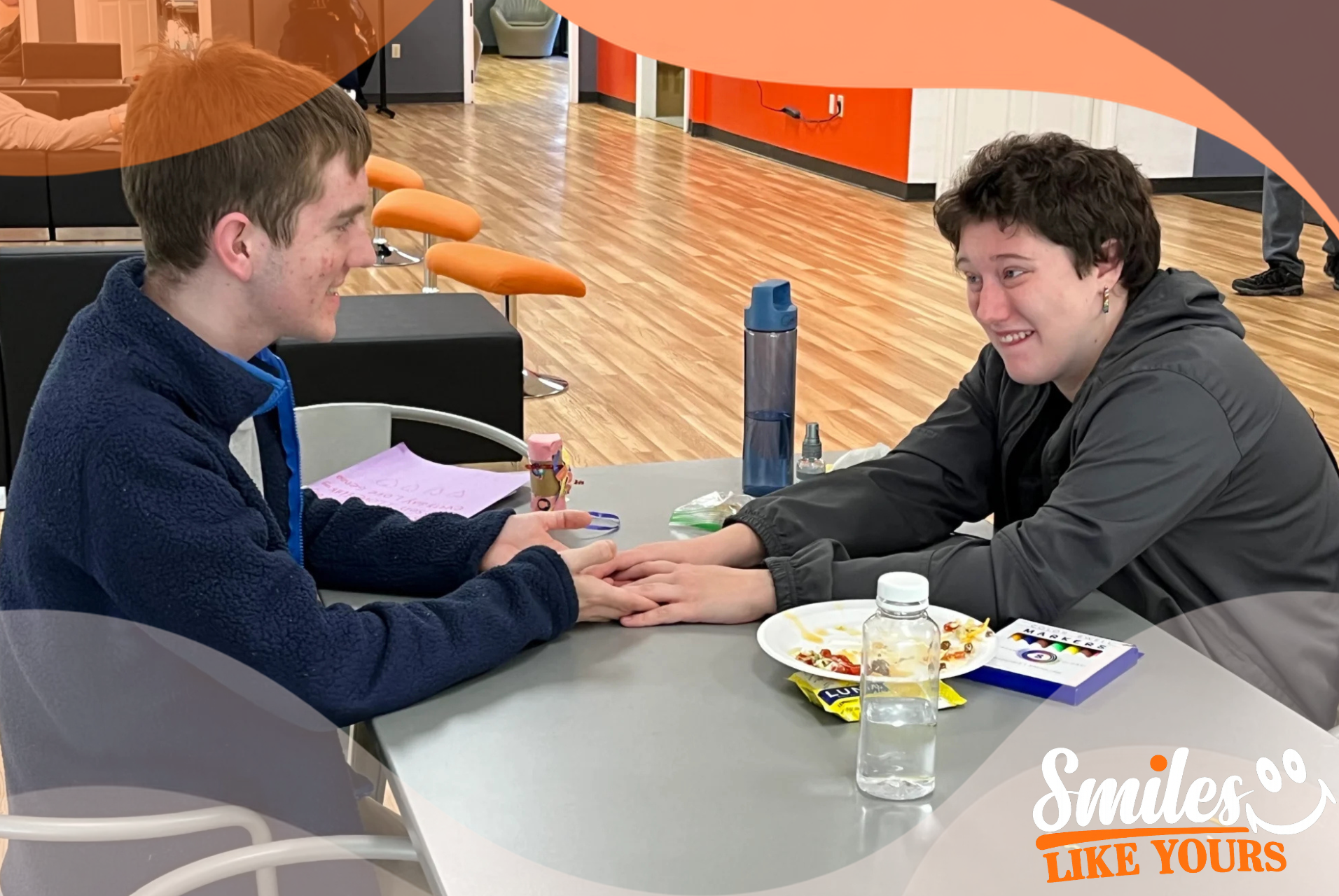 Two autistic adults smiling and connecting during a social activity at Smiles Like Yours in Virginia.