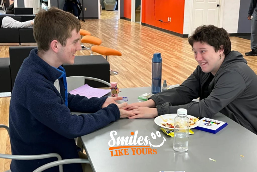Two adults smiling and interacting across a table during a structured social activity.
