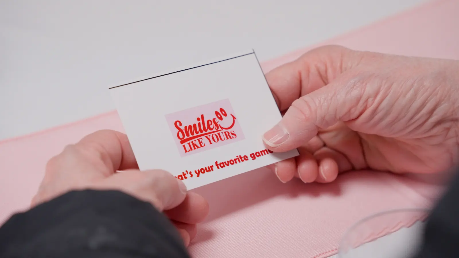 Conversation Prompt for Social Skills Practice Hands holding a Smiles Like Yours conversation prompt card during a social activity