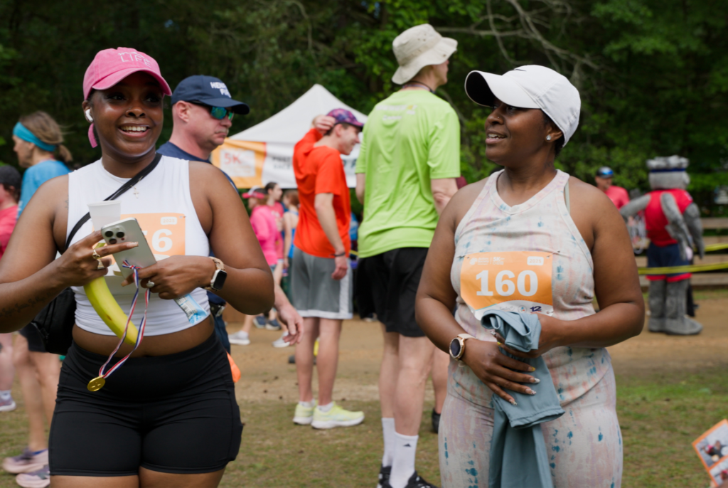 Two women smiling and talking after participating in a community 5K event in Virginia.